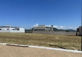 Vista externa de uma propriedade com um campo gramado e edifícios ao fundo.