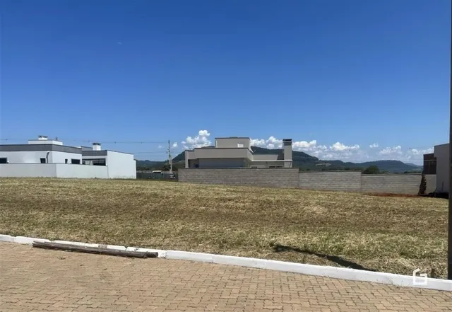 Vista externa de uma propriedade com um campo gramado e edifícios ao fundo.