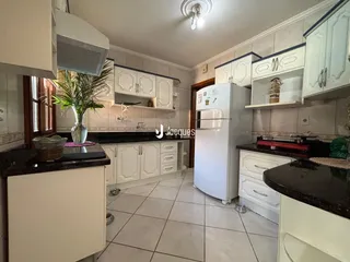 Imagem de uma cozinha com armários brancos e bancadas escuras.
