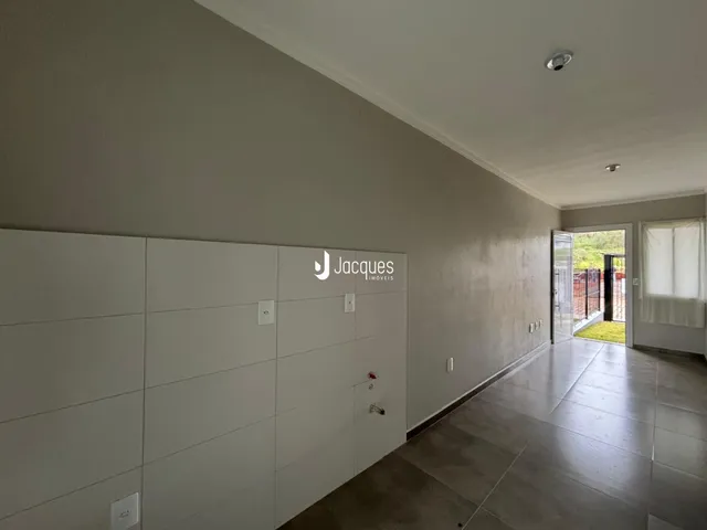 Corredor interno de uma residência com paredes brancas e piso claro.