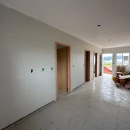 Corredor interno com paredes brancas e portas de madeira.