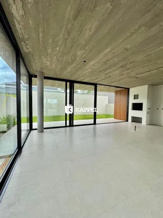 Ambiente interno amplo com piso de concreto e grandes portas de vidro que dão vista para o exterior.