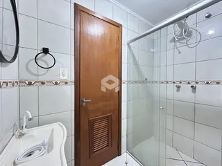 Foto de um banheiro com azulejos brancos e porta de madeira.