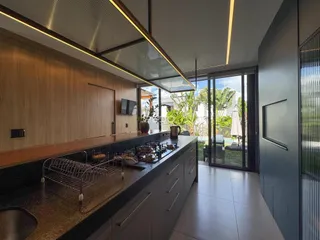 Vista da cozinha moderna com bancada escura e acesso a uma área externa através de portas de vidro.