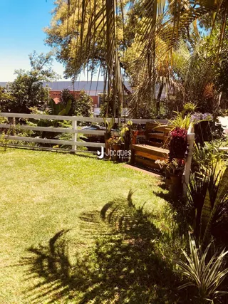 Jardim gramado com cerca de madeira e vegetação ao ar livre.
