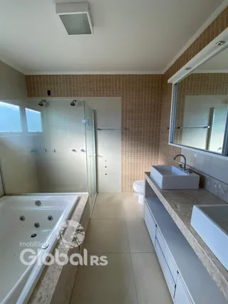Foto de um banheiro com banheira e box de vidro em uma residência.