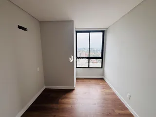 Interior de um corredor com piso de madeira e janela com vista para a cidade.