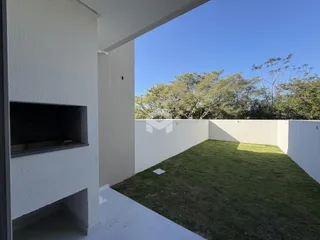 Vista de um quintal com gramado e muro branco.