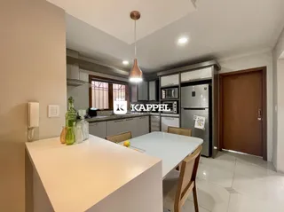 Cozinha moderna com bancada branca e armários escuros em um ambiente bem iluminado.