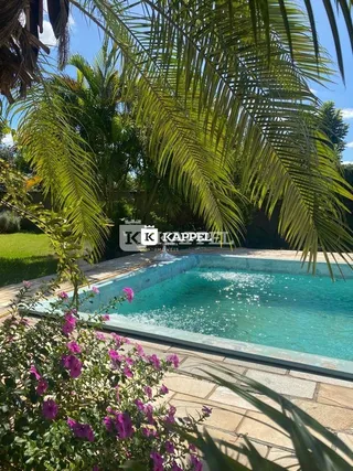 Foto da piscina externa cercada por vegetação tropical exuberante.