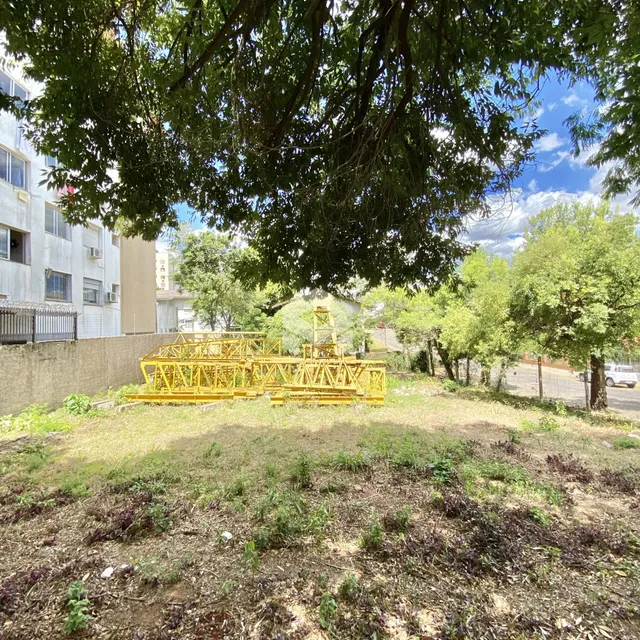 Vista externa de um terreno com vegetação e uma estrutura metálica amarela.