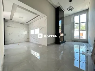 Sala de estar ampla com piso claro e paredes brancas.