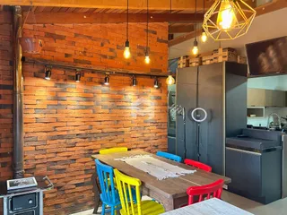 Uma sala de jantar com parede de tijolos aparentes e mesa de madeira.