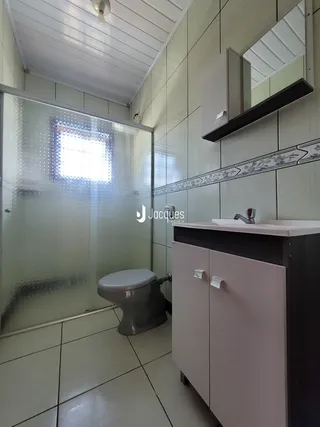 Interior de um banheiro com box de vidro e revestimento cerâmico.