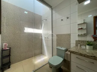 Banheiro com box de vidro e revestimento de cerâmica.