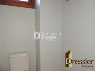 Foto de um ambiente interno com uma parede branca e um vaso sanitário.