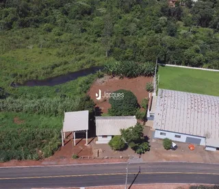 Vista externa da propriedade com vegetação e um curso d'água ao fundo.