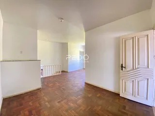 Vista interna de um corredor com piso de madeira no imóvel.