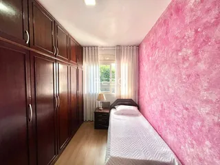 Quarto com armário de madeira e parede rosa vibrante.