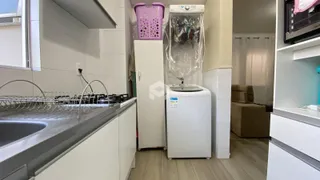 Vista de uma área de cozinha com bancada e máquina de lavar roupa.
