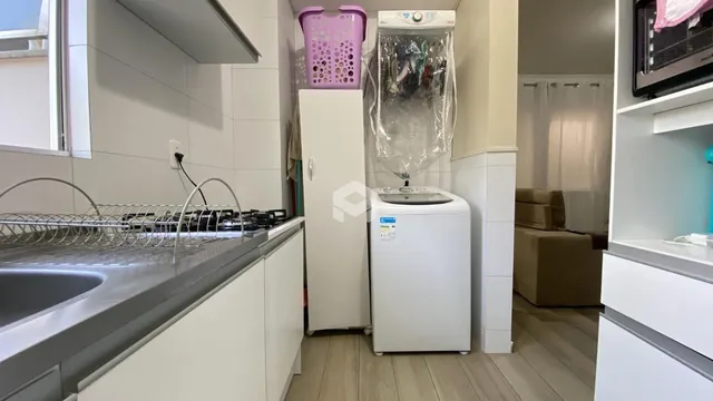 Vista de uma área de cozinha com bancada e máquina de lavar roupa.
