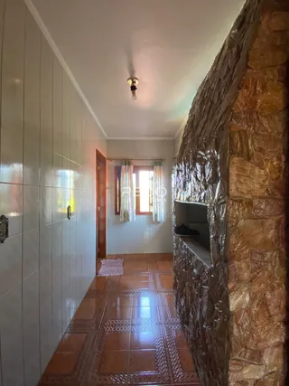 Corredor interno com piso de cerâmica e parede de pedra.