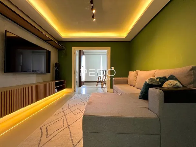 Sala de estar com parede verde e iluminação embutida.