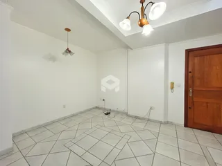 Foto de uma sala ampla com piso de cerâmica e paredes brancas.