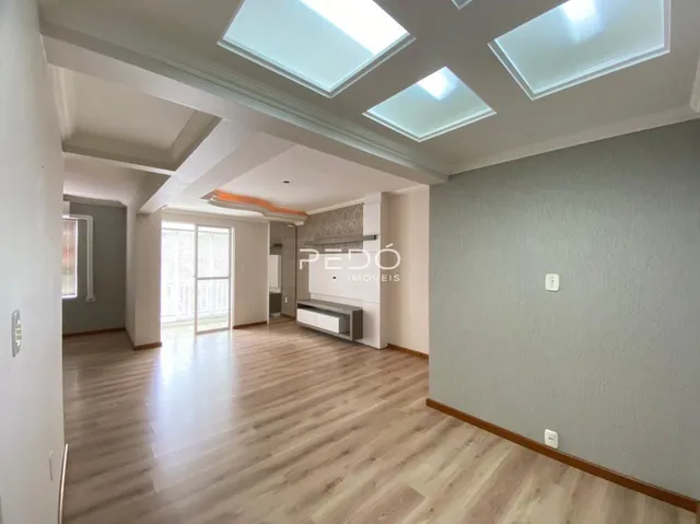 Sala de estar com teto de claraboias e piso de madeira clara.