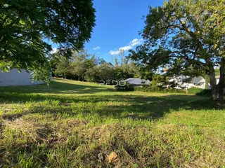 Vista externa de um terreno gramado com árvores ao fundo.