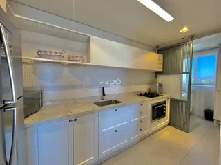 Cozinha moderna com armários brancos e bancadas claras.