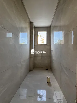 Corredor interno com paredes claras e janela no final.