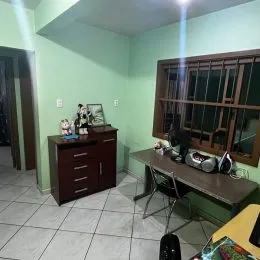 Sala de estar com paredes verdes e móveis de madeira escura.