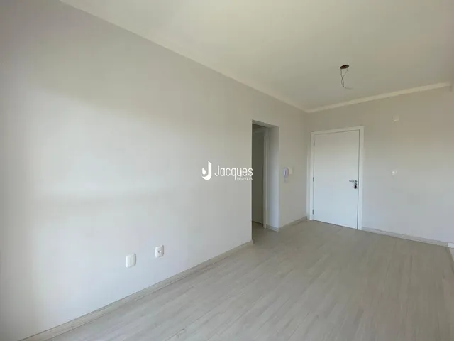 Vista interna de um ambiente com piso de madeira clara e paredes brancas.