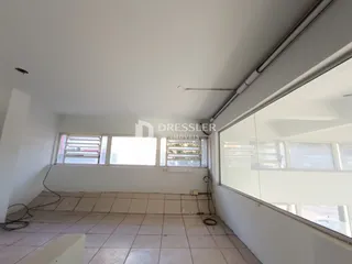 Vista interna de uma sala com piso de cerâmica e janelas.
