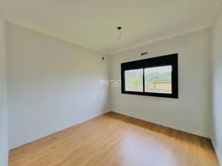 Vista interna de uma sala com piso de madeira clara e parede branca.