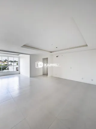 Sala ampla com piso claro e grande janela de vista para a paisagem.
