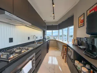 Cozinha moderna com armários escuros e vista para a paisagem externa.