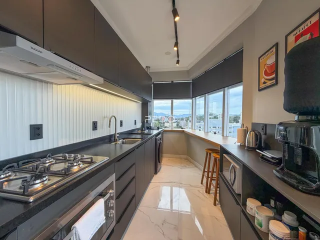 Cozinha moderna com armários escuros e vista para a paisagem externa.
