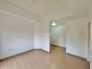 Interior de um corredor com piso de madeira clara e paredes brancas.