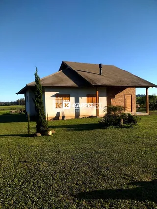 Fachada de uma casa de tijolos com telhado de telhas em um terreno gramado.