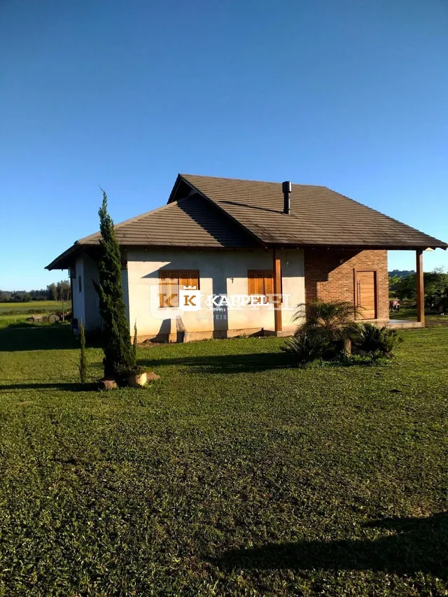 Fachada de uma casa de tijolos com telhado de telhas em um terreno gramado.
