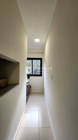 Corredor interno de uma residência com paredes brancas e piso claro.