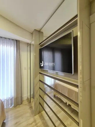 Imagem de uma sala de estar com televisão montada na parede.