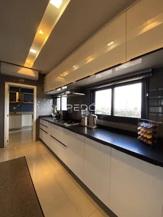 Foto de uma cozinha moderna com armários brancos e bancadas escuras.