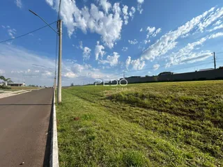 Vista da propriedade com campo gramado e estrada ao lado.