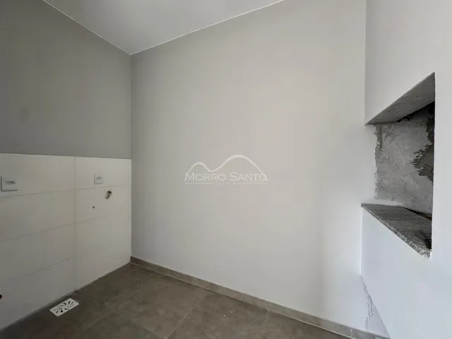 Hall de entrada com paredes brancas e piso de cerâmica.