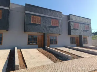 Fachada externa de uma residência moderna com revestimento escuro e detalhes em madeira.
