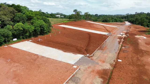 Vista aérea de um terreno aberto com solo avermelhado e áreas de terraplanagem.