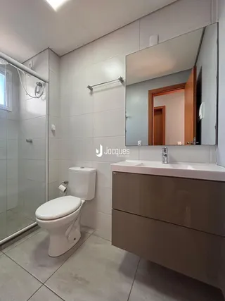 Banheiro com piso de cerâmica e box de vidro transparente.